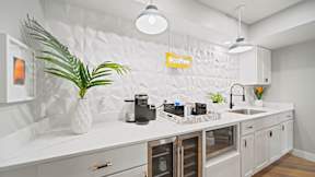 a white kitchen with white cabinets and a green plant in a white vase