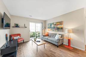 A living room with a grey couch, a red chair, a black table, and a painting on the wall.