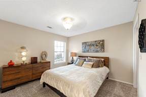 A bedroom with a bed, dresser, and window.