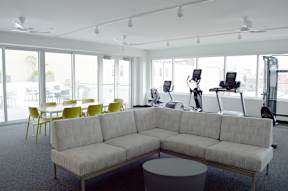 A white couch sits in a room with a grey carpet.