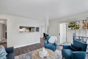a living room with blue couches and chairs and a kitchen with a sliding door