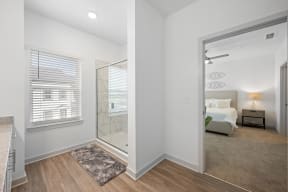 a white bedroom with a large window and a glass shower