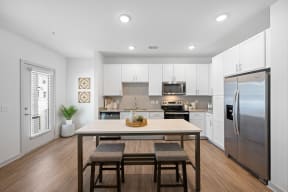 a large kitchen with stainless steel appliances and a wooden table