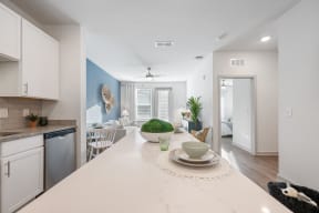 an open kitchen and living room with white cabinets and a white counter top and a