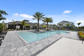 a large swimming pool with palm trees and buildings in the background