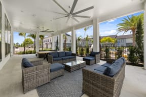 a covered patio with wicker furniture and a ceiling fan