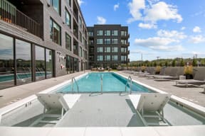 a swimming pool with lounge chairs in front of a building