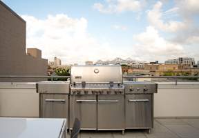 A stainless steel outdoor grill on a rooftop patio.