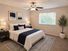 A bedroom with a bed, a ceiling fan, and a window.