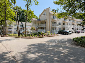 A sunny day at a residential complex with a black car parked in the driveway.
