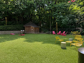 A backyard with a lawn, chairs, and a gazebo.