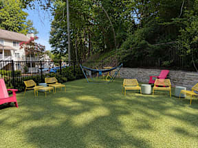 A backyard with a hammock, lawn chairs, and a trampoline.