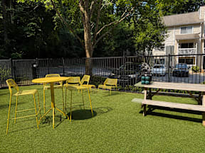 A yellow table and chairs are set up on a green lawn.
