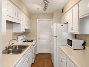 A small kitchen with white cabinets and appliances.