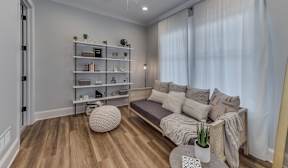 A living room with a couch, a coffee table, and a shelf with various items.