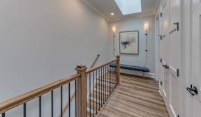 A hallway with a wooden floor and a skylight.