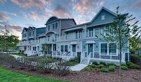 A large, two-story house with a wrap-around porch and a well-maintained lawn.