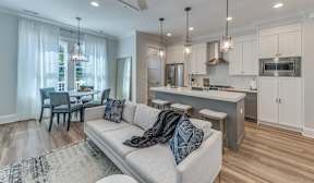 A modern kitchen with a breakfast bar and a living room with a couch.
