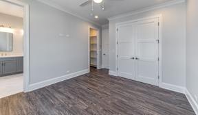A room with white walls and wooden flooring with a large white wardrobe.