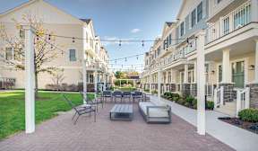 A sunny day at a residential area with apartment buildings and a patio with furniture.