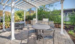 A patio with a table and chairs under a white pergola.