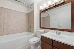 A white toilet sits next to a white bathtub in a bathroom.