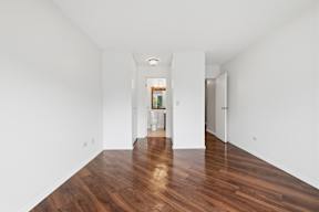 A long hallway with wood floors and white walls.