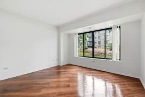 Empty room with wooden floor and large windows.