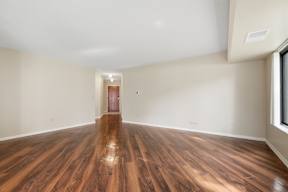 A room with wooden flooring and a doorway leading to another room.