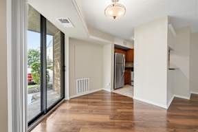 A room with a wooden floor and a refrigerator in it.