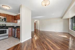 A kitchen with wooden floors and a white wall.