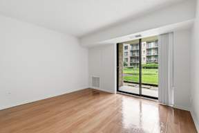 A room with a wooden floor and a sliding glass door leading to a balcony.