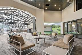 A modern outdoor seating area with a glass wall and a metal roof.