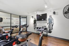 A room with exercise bikes and a television mounted on the wall.