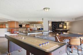 A billiard table is in the middle of a room with chairs and a bar.