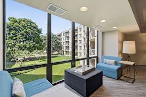 A modern living room with a view of a green lawn and trees.