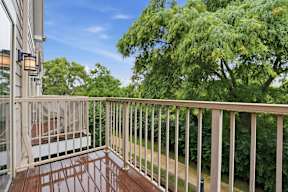 A balcony with a railing and a tree in the background.