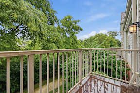 A balcony with a white railing overlooks a lush green yard.