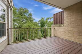 A wooden deck with a metal railing and a brick wall.