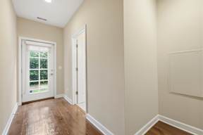 A hallway with a white door and a window.
