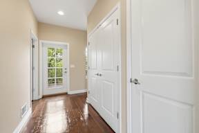 A hallway with white doors and a window.