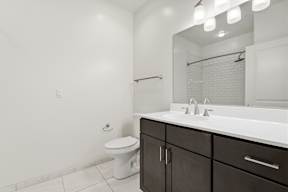 A white bathroom with a toilet, sink, and mirror.
