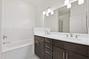 A white bathroom with a black vanity and a white bathtub.