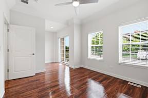 A room with a white door, a window with blinds, and a ceiling fan.