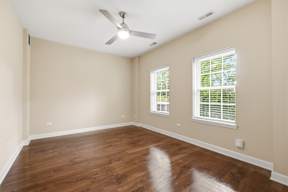 A room with a ceiling fan and two windows.