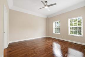 A room with a ceiling fan and wooden flooring.