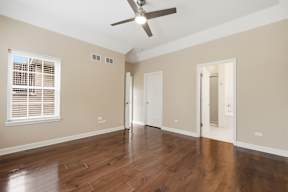 A room with a ceiling fan and wooden floors.