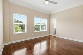 A room with a ceiling fan and two windows.