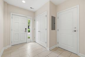 A hallway with three white doors and a tiled floor.