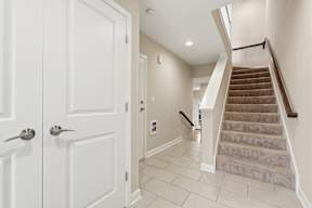 A hallway with a staircase and a white door.